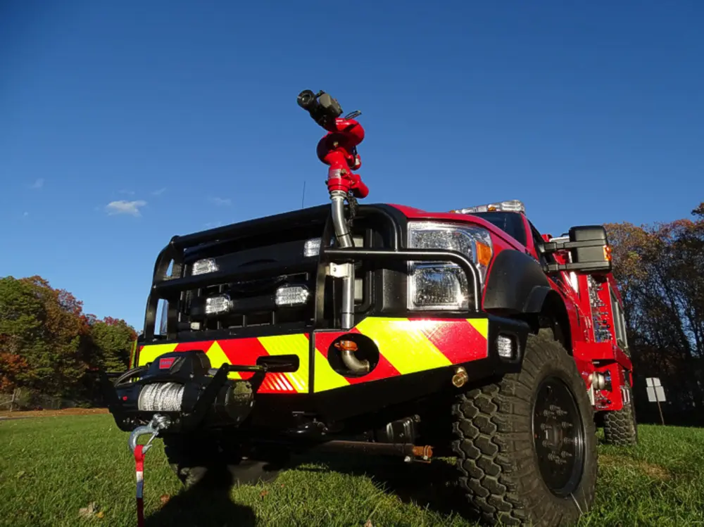 Exterior view of small fire truck showing cab, body compartments, and wheel/tire area.