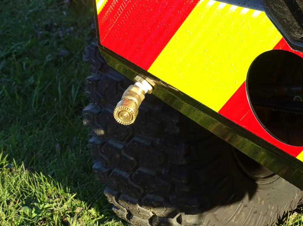 Exterior view of small fire truck showing cab, body compartments, and wheel/tire area.
