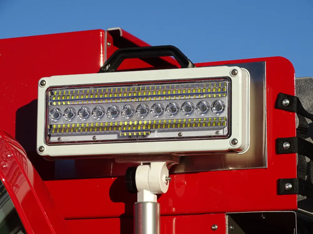 Exterior view of small fire truck showing cab, body compartments, and wheel/tire area.