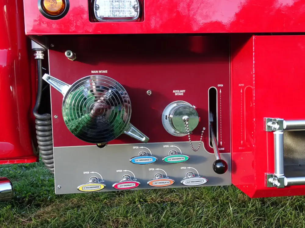 Exterior view of small fire truck showing cab, body compartments, and wheel/tire area.