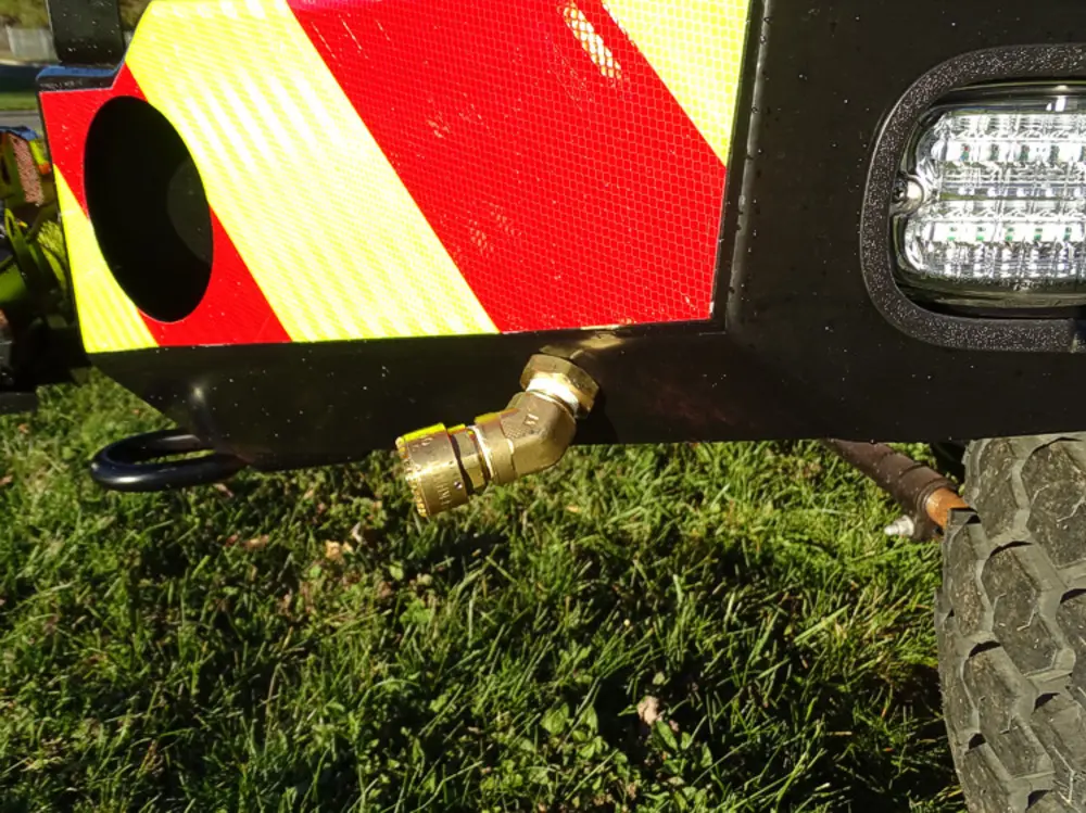 Exterior view of small fire truck showing cab, body compartments, and wheel/tire area.