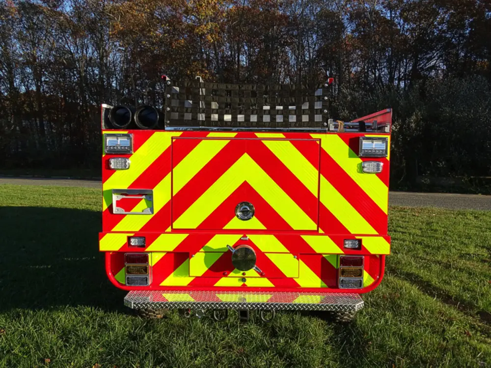 Exterior view of small fire truck showing cab, body compartments, and wheel/tire area.