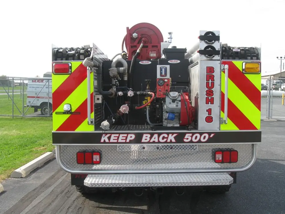 Exterior view of small fire truck showing cab, body compartments, and wheel/tire area.