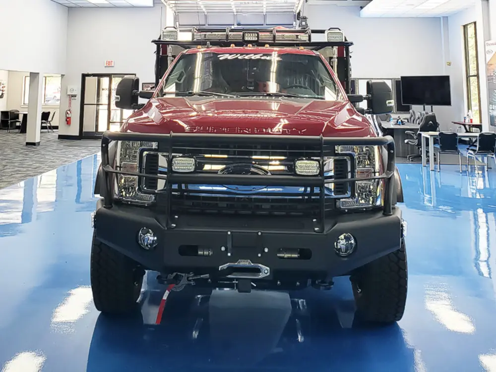 Exterior view of small fire truck showing cab, body compartments, and wheel/tire area.