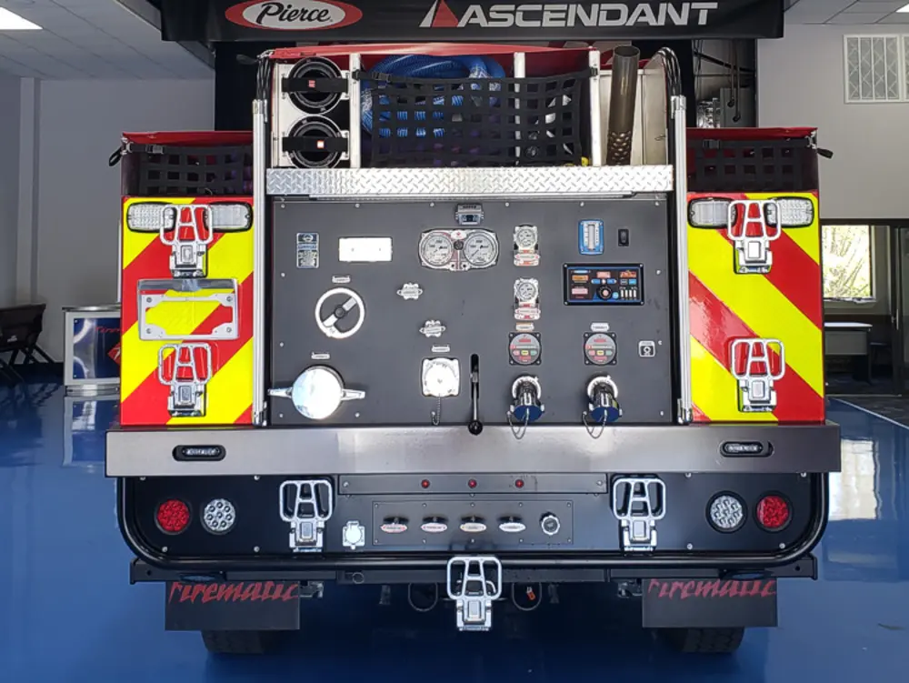 Exterior view of small fire truck showing cab, body compartments, and wheel/tire area.
