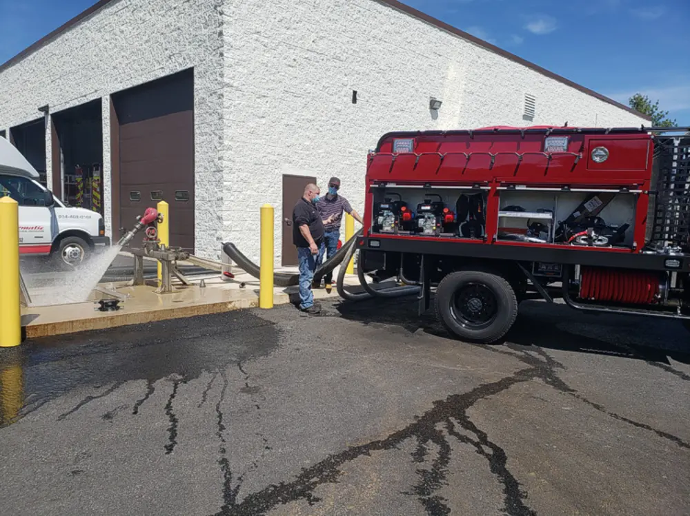 Exterior view of small fire truck showing cab, body compartments, and wheel/tire area.