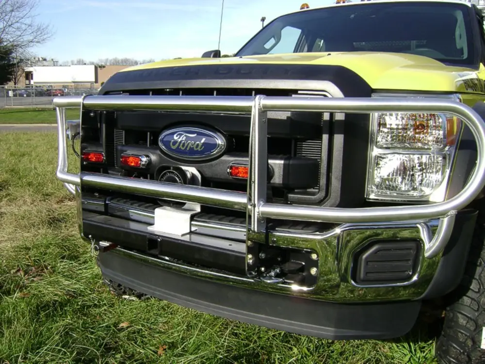 Exterior view of small fire truck showing cab, body compartments, and wheel/tire area.