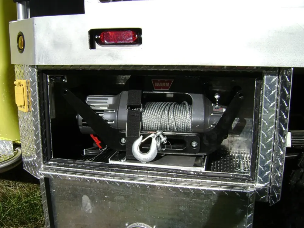 Exterior view of small fire truck showing cab, body compartments, and wheel/tire area.