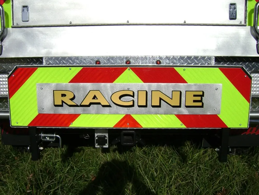 Exterior view of small fire truck showing cab, body compartments, and wheel/tire area.