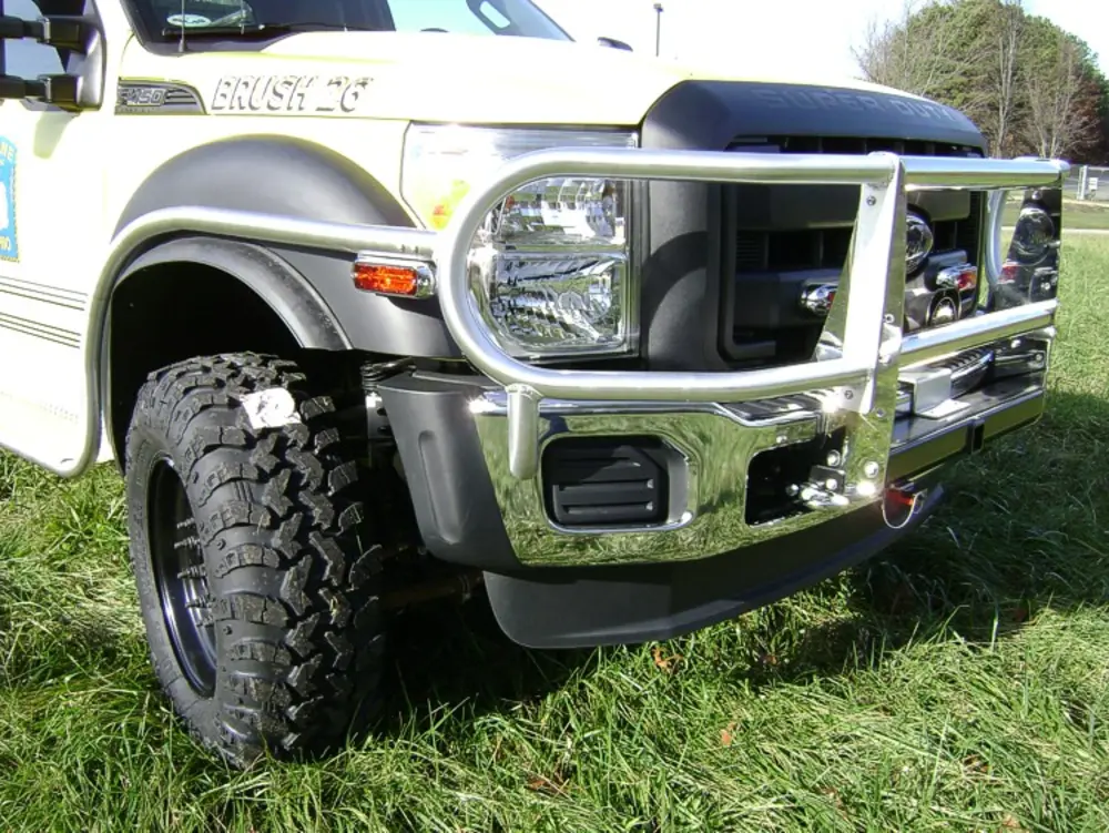 Exterior view of small fire truck showing cab, body compartments, and wheel/tire area.