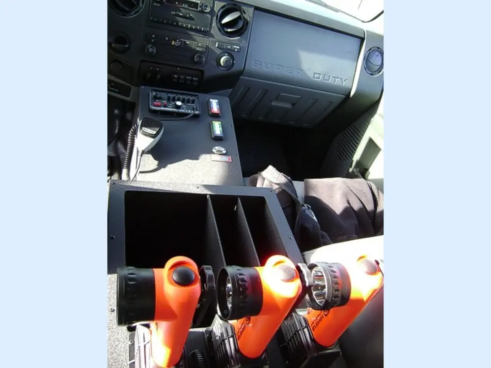 Exterior view of small fire truck showing cab, body compartments, and wheel/tire area.