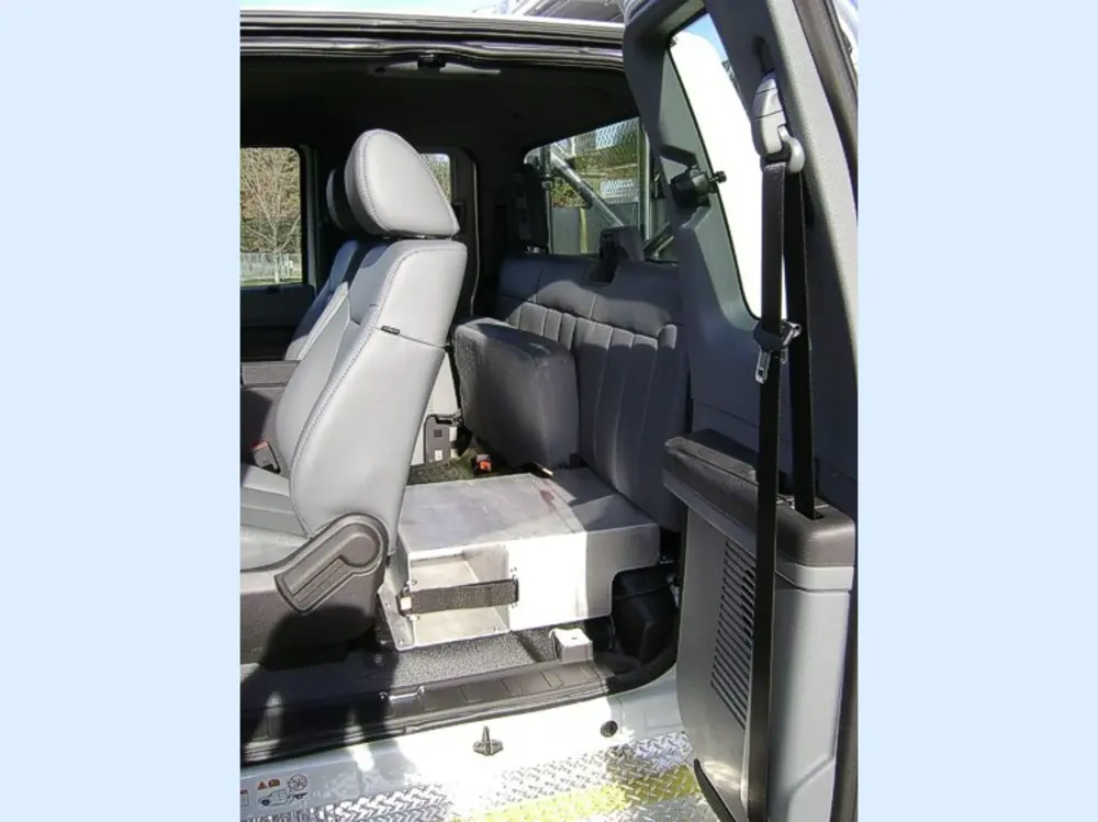 Exterior view of small fire truck showing cab, body compartments, and wheel/tire area.