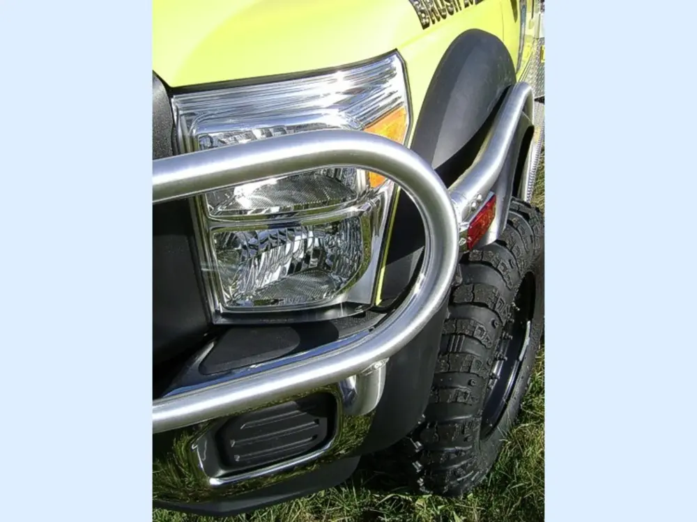 Exterior view of small fire truck showing cab, body compartments, and wheel/tire area.
