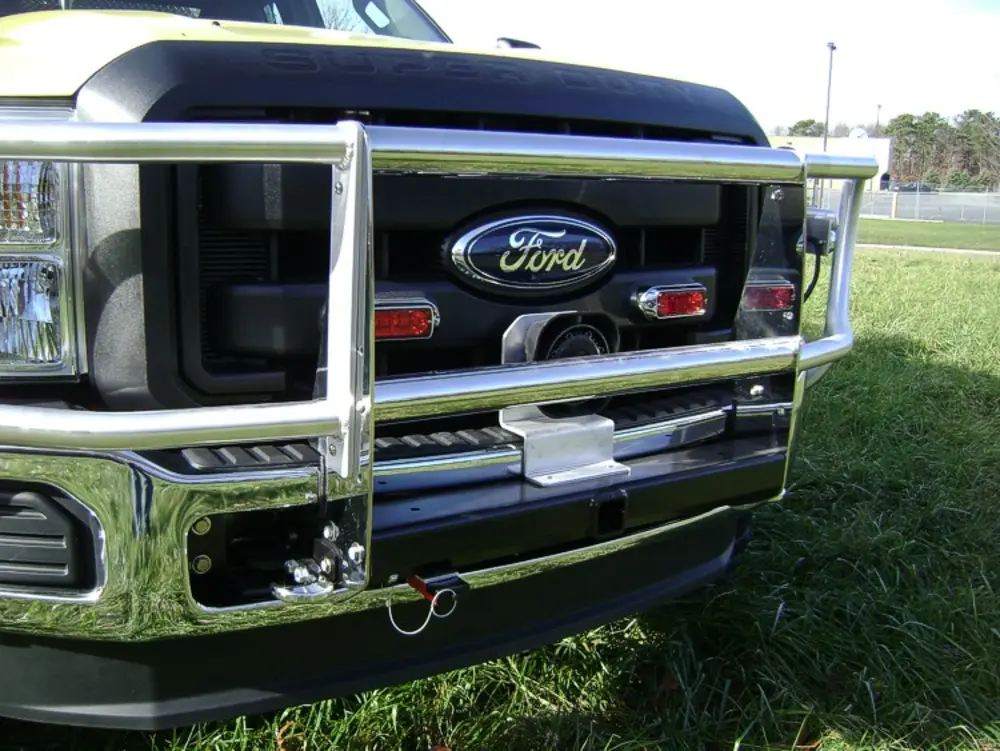 Exterior view of small fire truck showing cab, body compartments, and wheel/tire area.