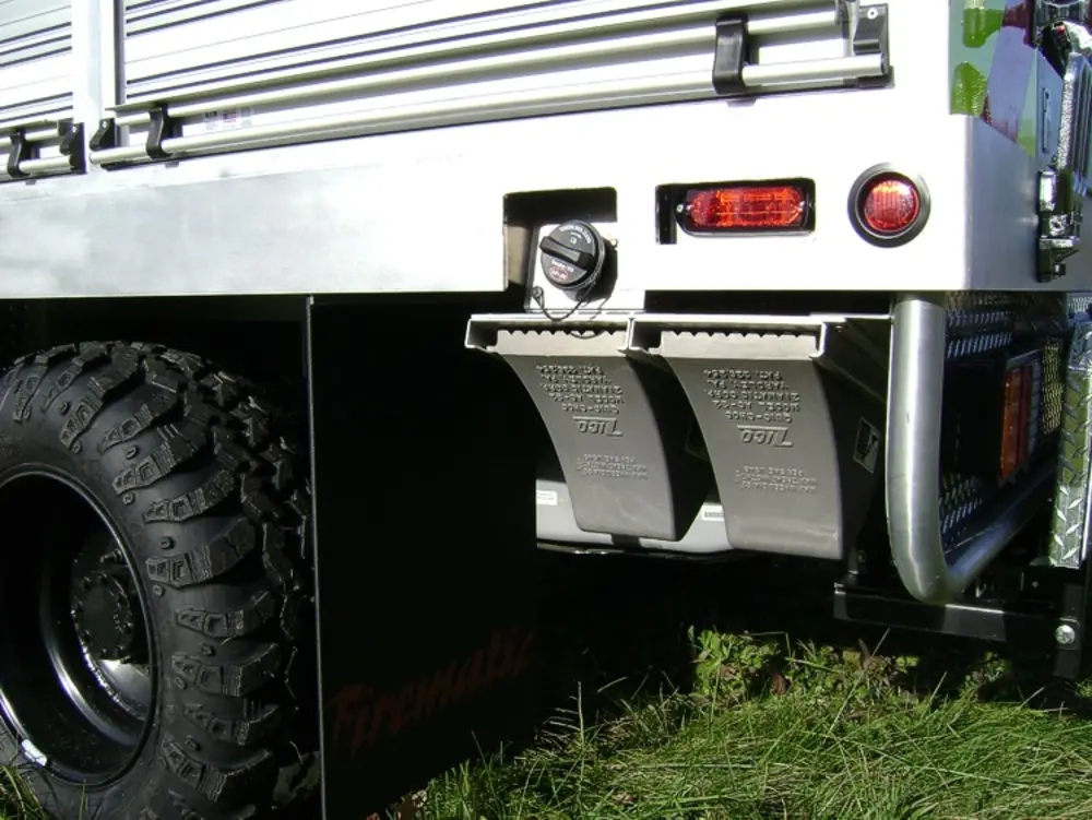Exterior view of small fire truck showing cab, body compartments, and wheel/tire area.