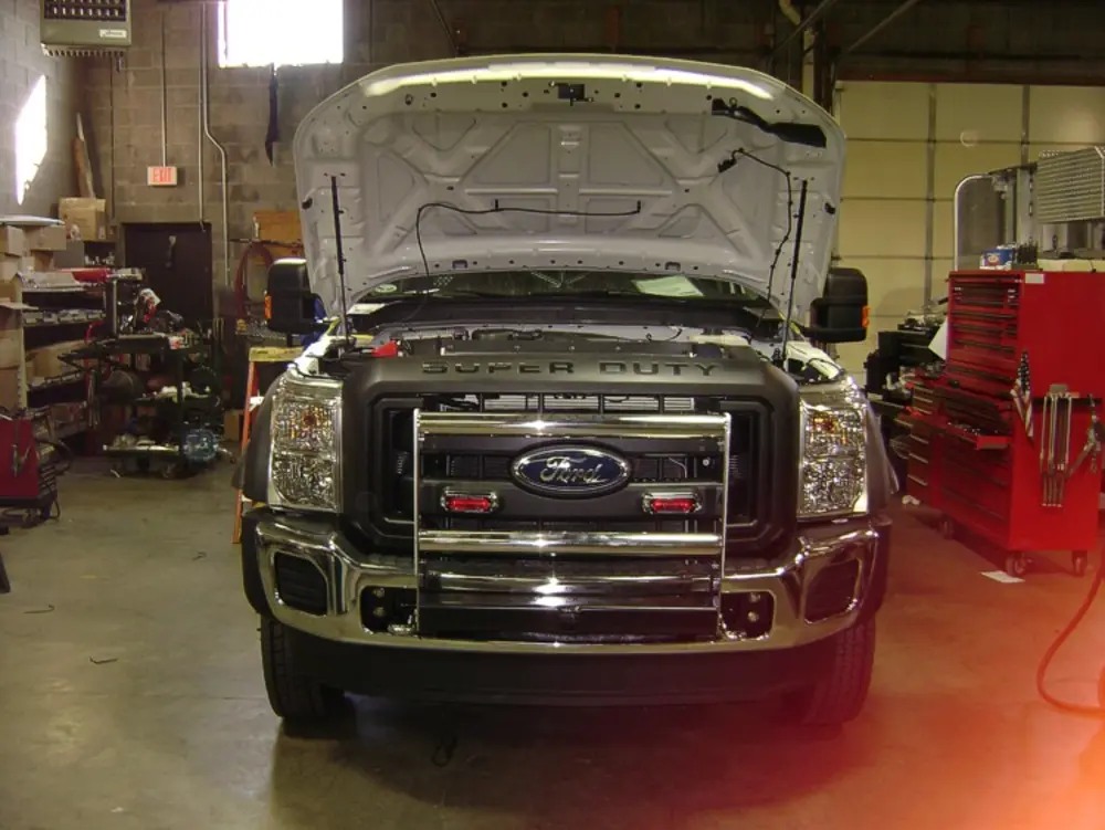 Exterior view of small fire truck showing cab, body compartments, and wheel/tire area.