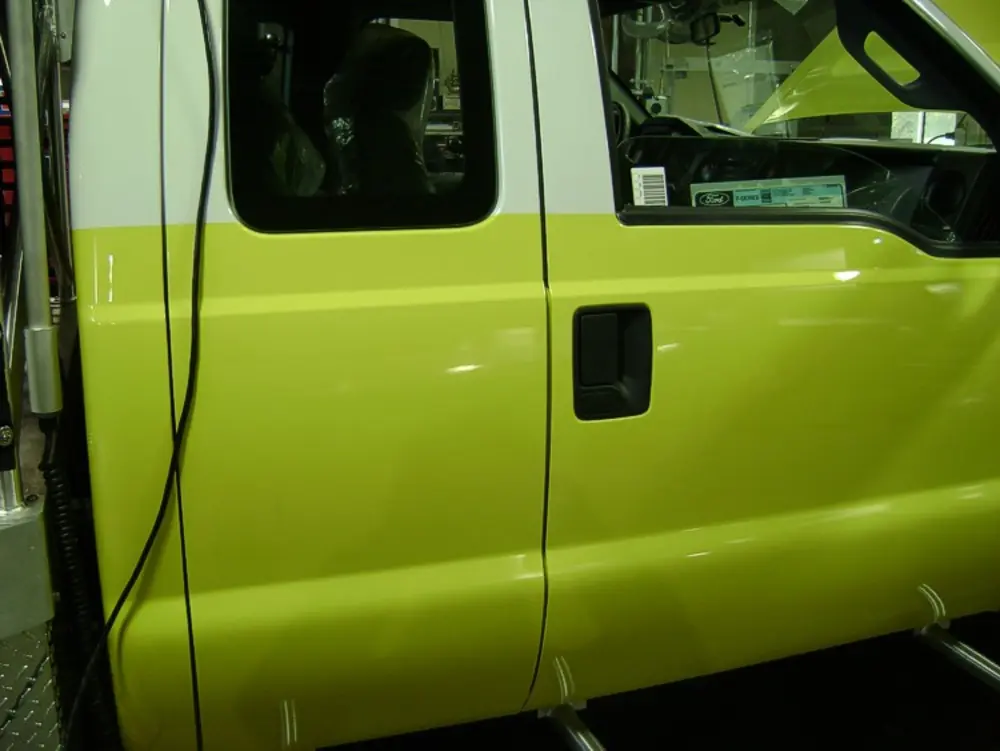 Exterior view of small fire truck showing cab, body compartments, and wheel/tire area.