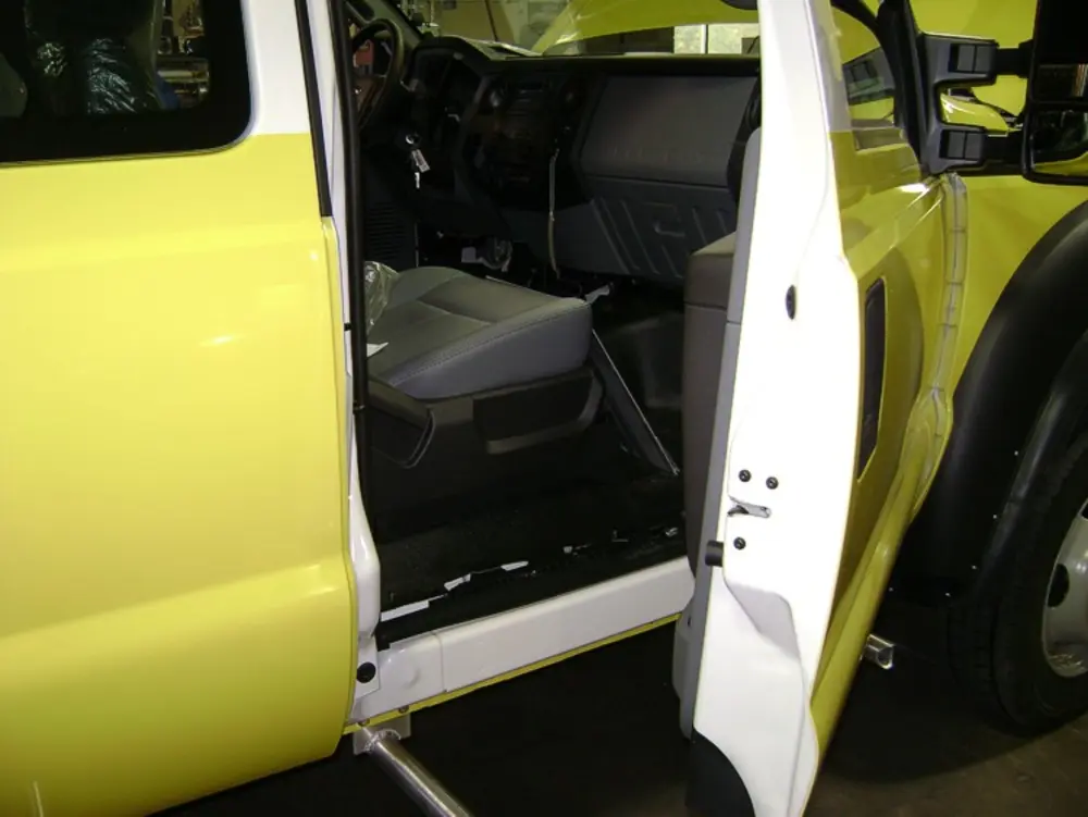 Exterior view of small fire truck showing cab, body compartments, and wheel/tire area.