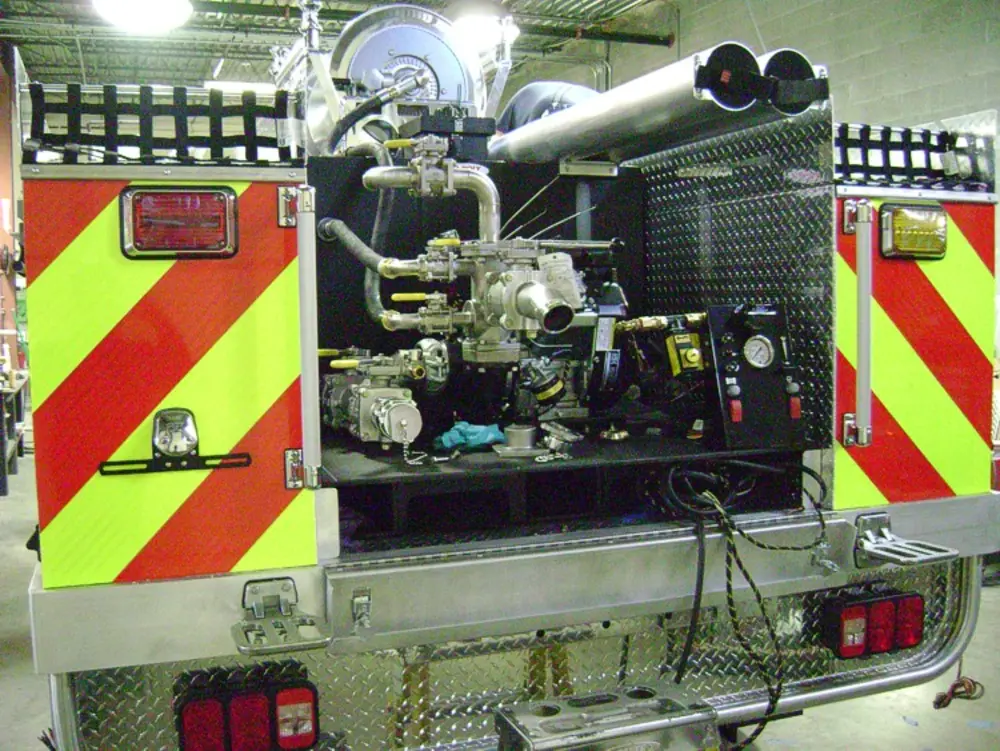 Exterior view of small fire truck showing cab, body compartments, and wheel/tire area.