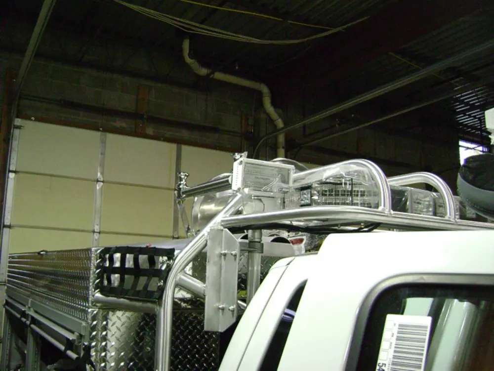 Exterior view of small fire truck showing cab, body compartments, and wheel/tire area.