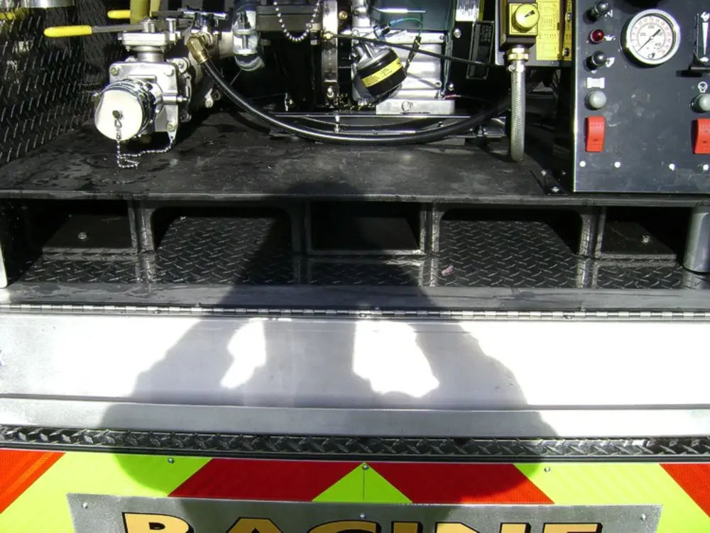 Exterior view of small fire truck showing cab, body compartments, and wheel/tire area.