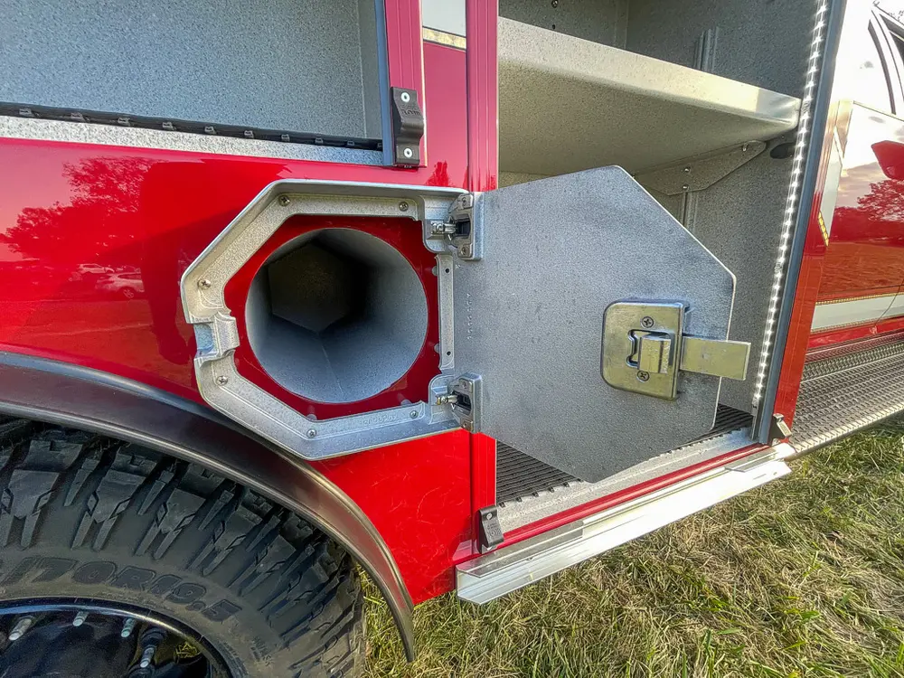 Exterior view of small fire truck showing cab, body compartments, and wheel/tire area.