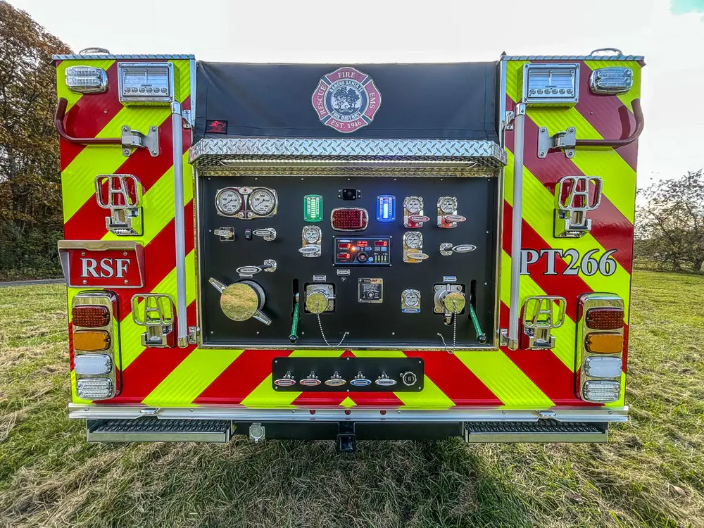 Exterior view of small fire truck showing cab, body compartments, and wheel/tire area.