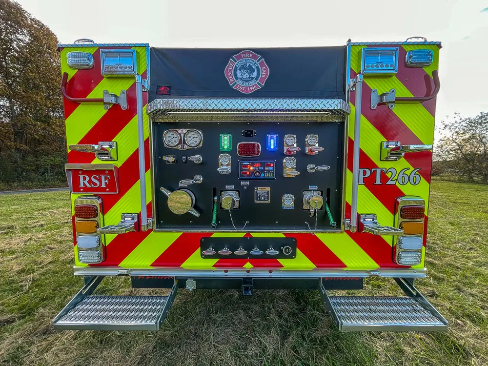 Exterior view of small fire truck showing cab, body compartments, and wheel/tire area.