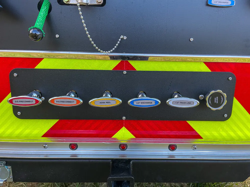 Exterior view of small fire truck showing cab, body compartments, and wheel/tire area.