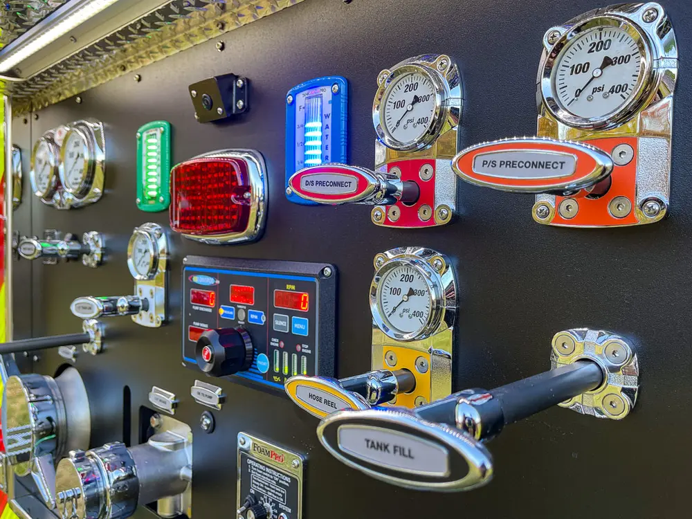 Exterior view of small fire truck showing cab, body compartments, and wheel/tire area.