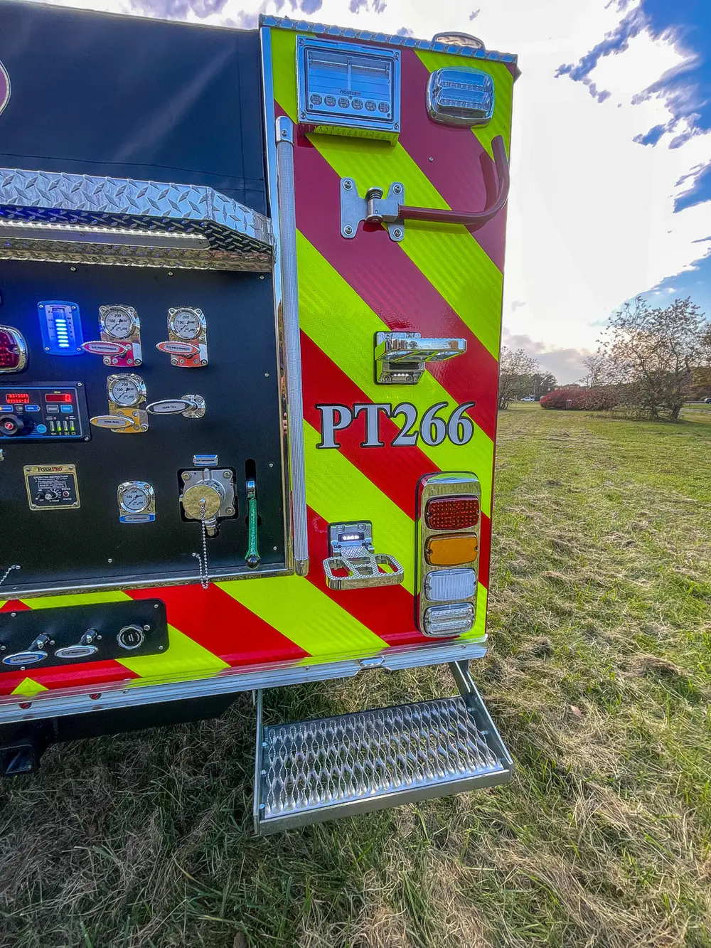 Exterior view of small fire truck showing cab, body compartments, and wheel/tire area.
