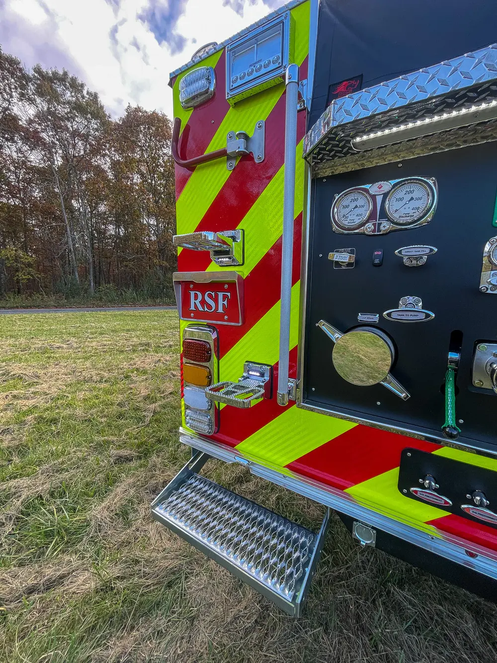 Exterior view of small fire truck showing cab, body compartments, and wheel/tire area.
