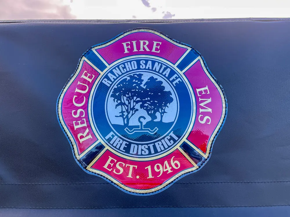 Exterior view of small fire truck showing cab, body compartments, and wheel/tire area.
