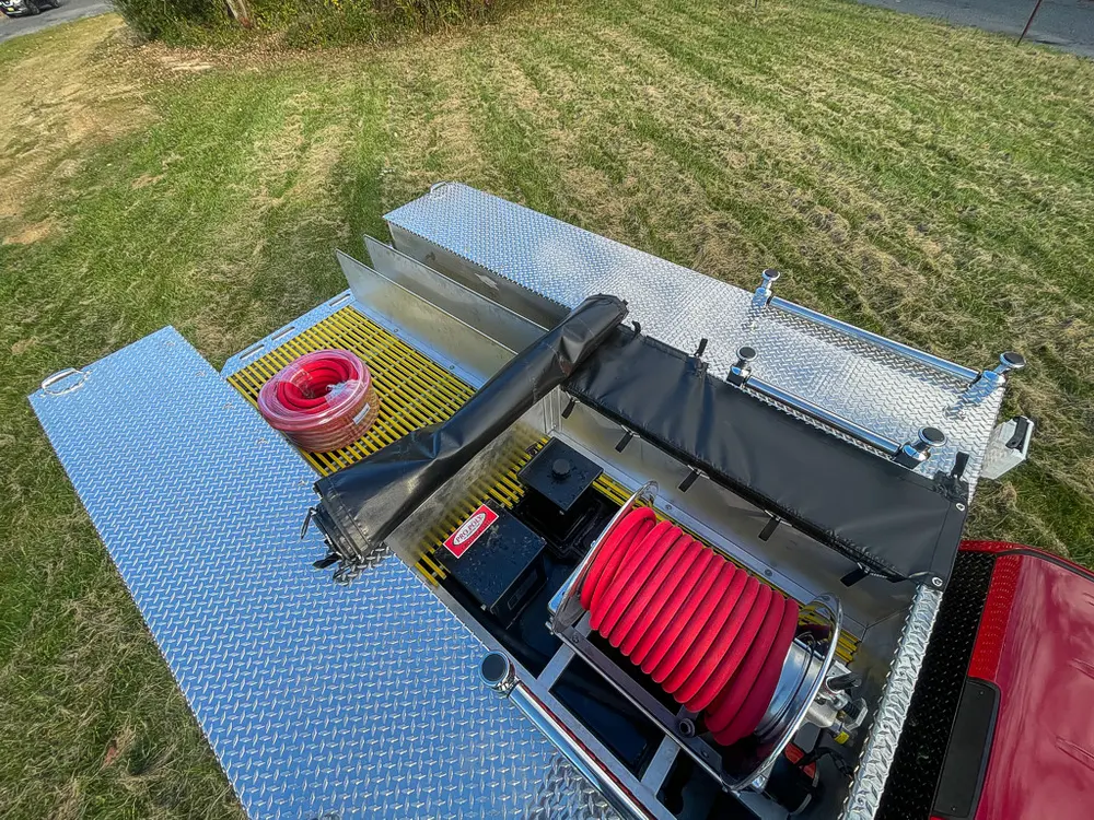 Exterior view of small fire truck showing cab, body compartments, and wheel/tire area.