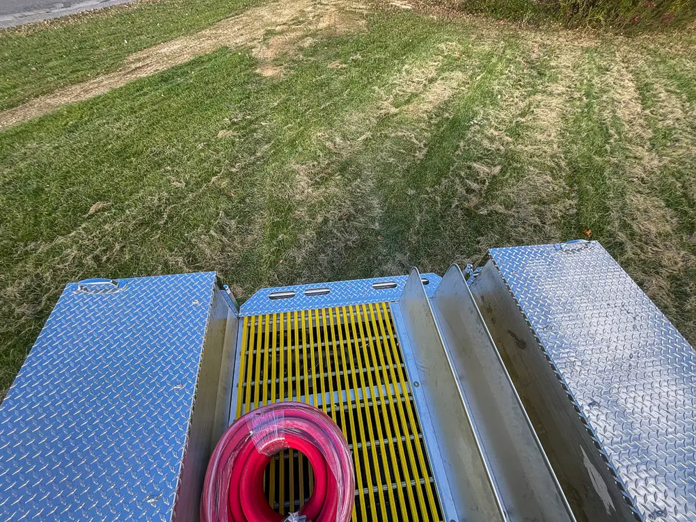 Exterior view of small fire truck showing cab, body compartments, and wheel/tire area.
