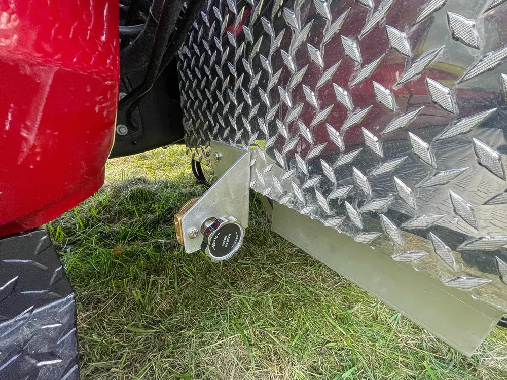 Exterior view of small fire truck showing cab, body compartments, and wheel/tire area.