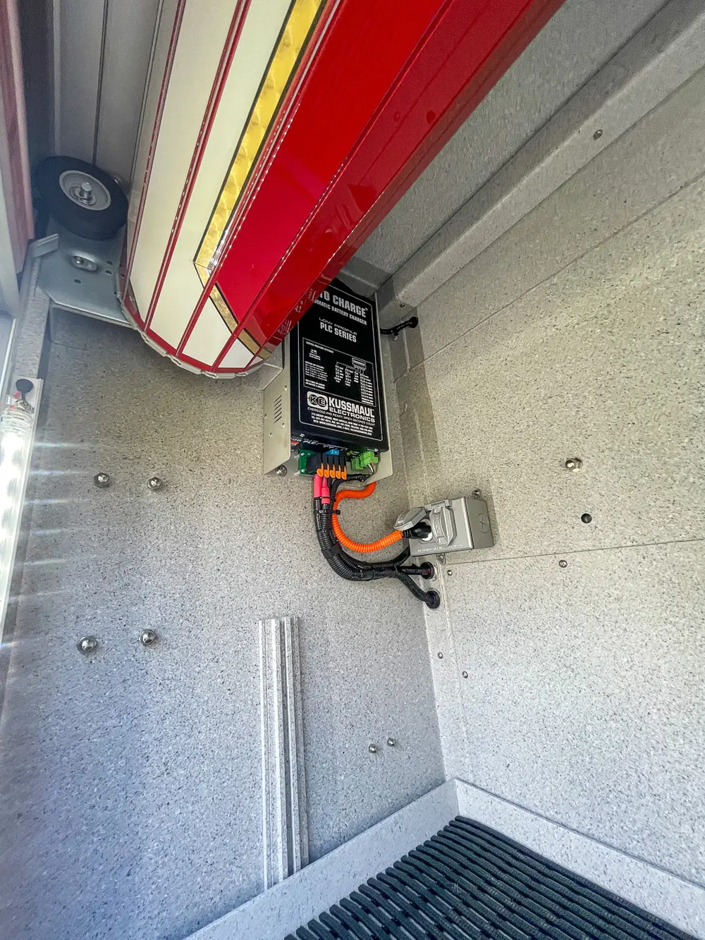 Exterior view of small fire truck showing cab, body compartments, and wheel/tire area.