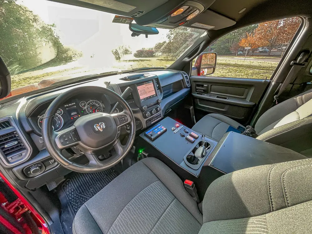 Exterior view of small fire truck showing cab, body compartments, and wheel/tire area.