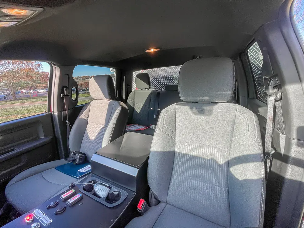 Exterior view of small fire truck showing cab, body compartments, and wheel/tire area.