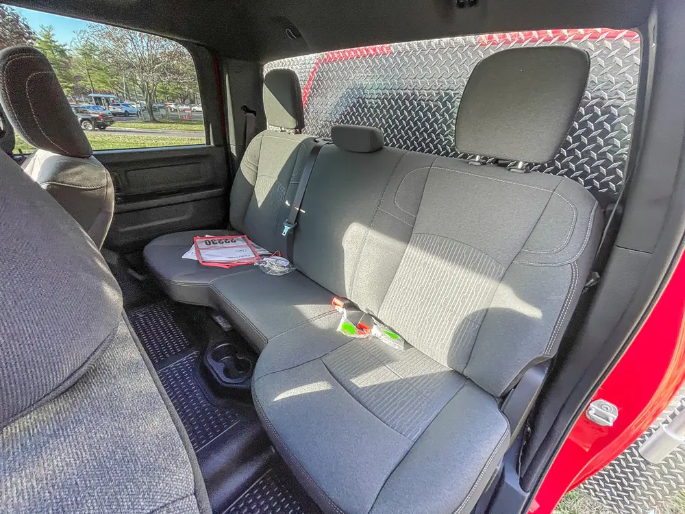 Exterior view of small fire truck showing cab, body compartments, and wheel/tire area.