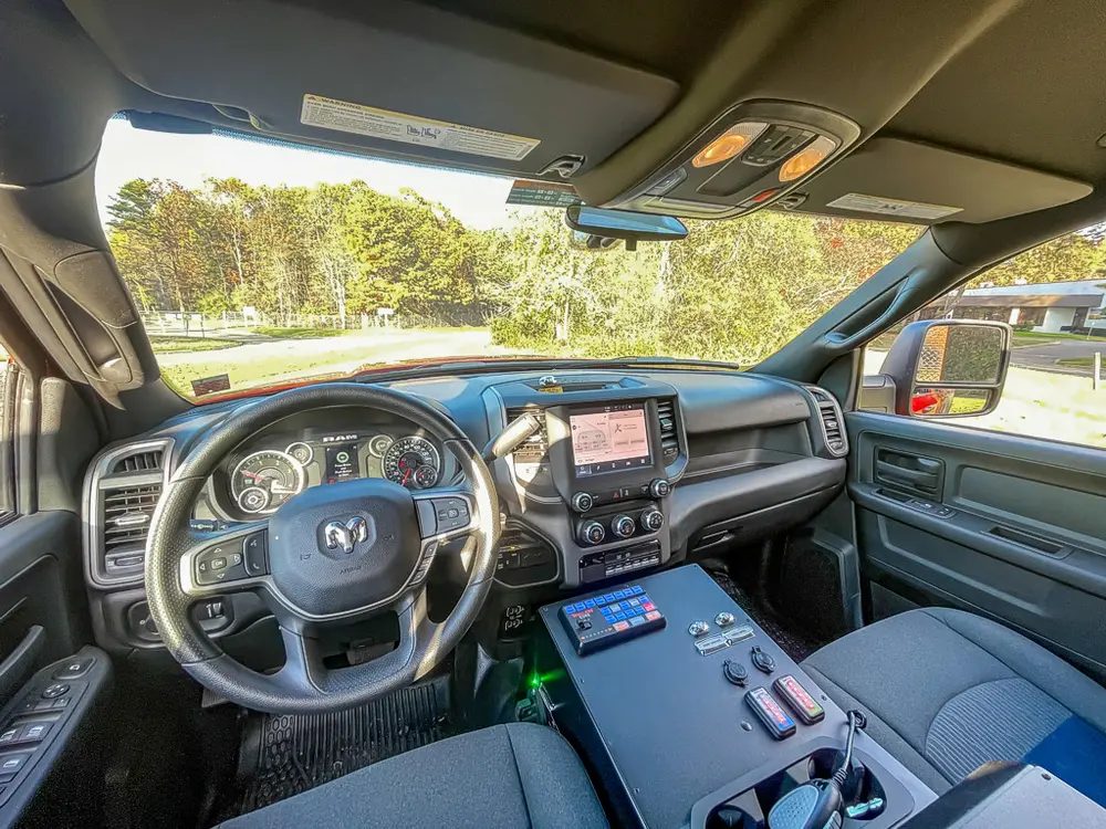 Exterior view of small fire truck showing cab, body compartments, and wheel/tire area.