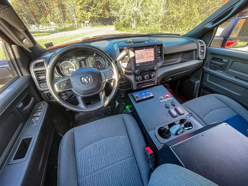 Exterior view of small fire truck showing cab, body compartments, and wheel/tire area.