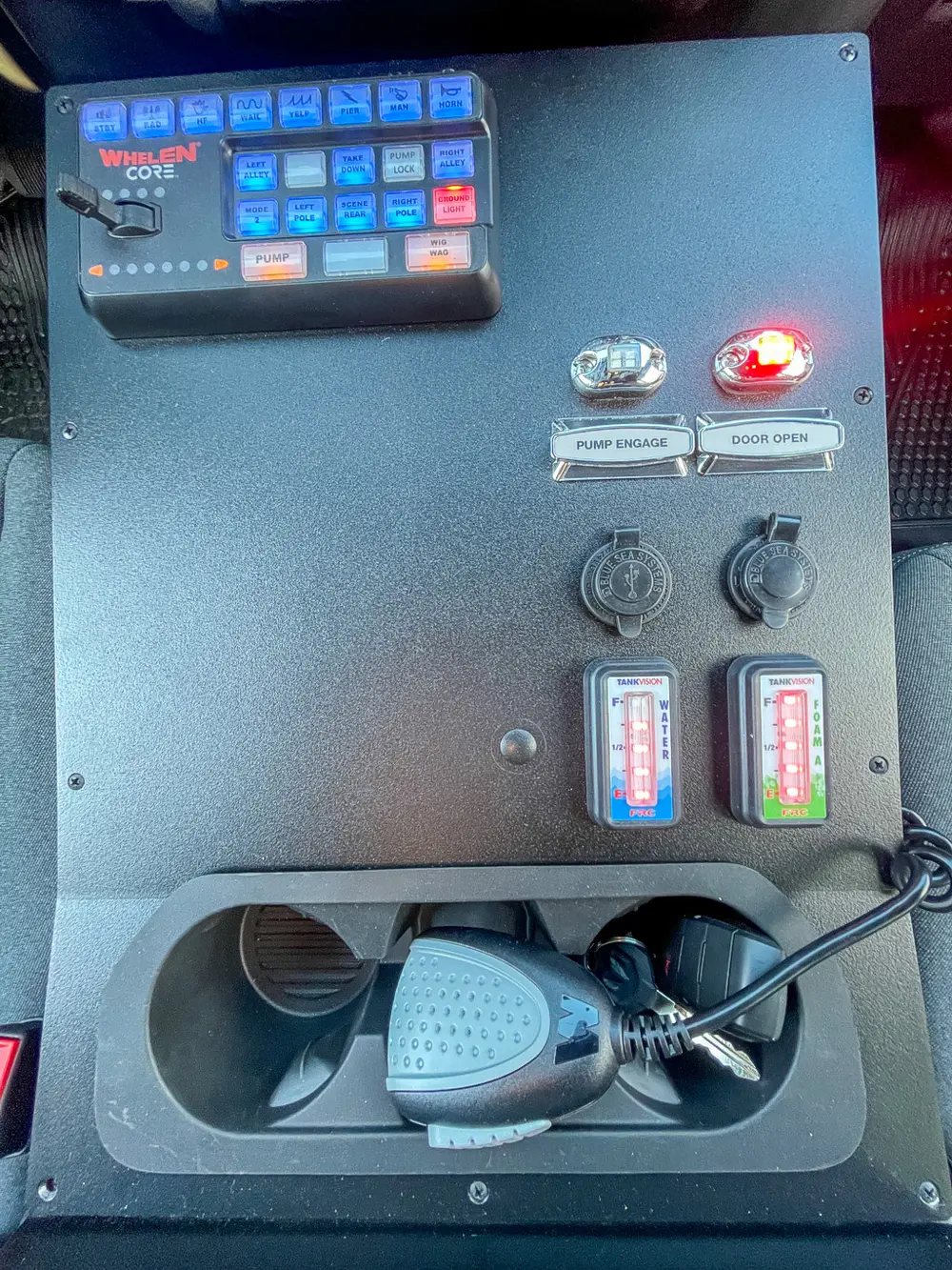 Exterior view of small fire truck showing cab, body compartments, and wheel/tire area.