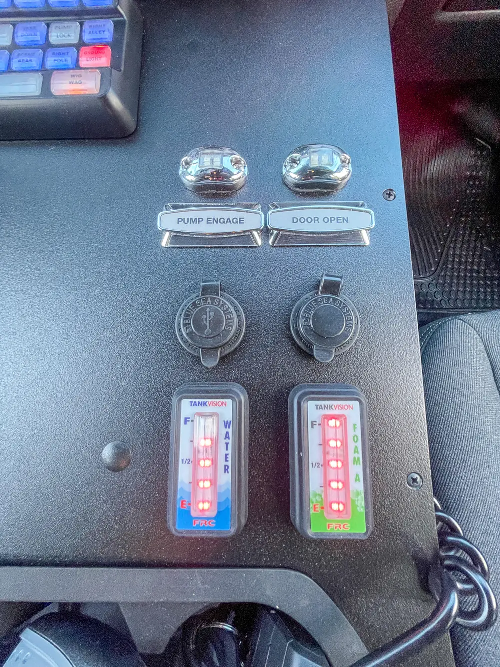 Exterior view of small fire truck showing cab, body compartments, and wheel/tire area.