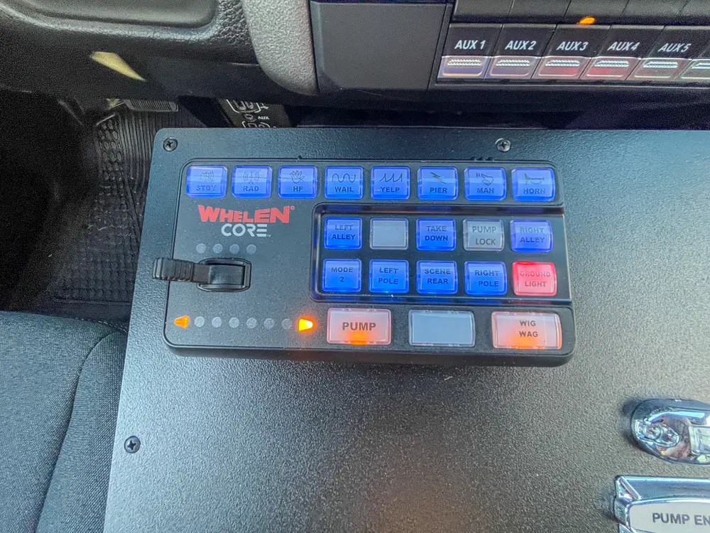 Exterior view of small fire truck showing cab, body compartments, and wheel/tire area.