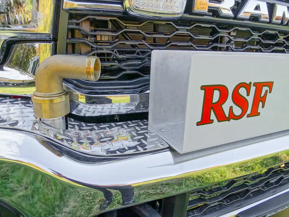 Exterior view of small fire truck showing cab, body compartments, and wheel/tire area.
