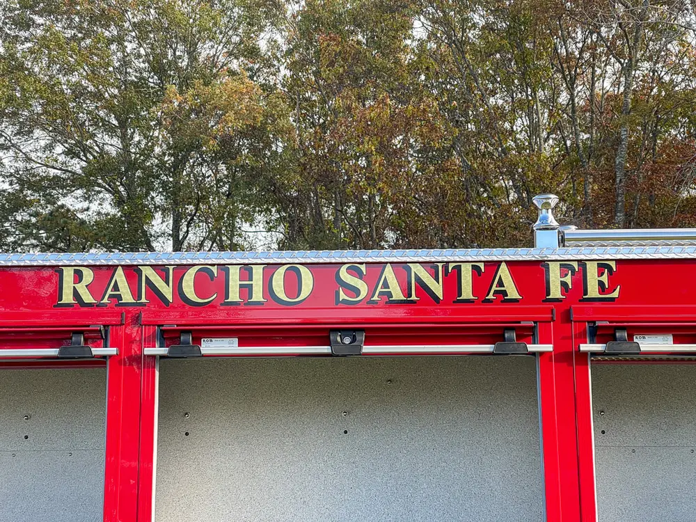 Exterior view of small fire truck showing cab, body compartments, and wheel/tire area.