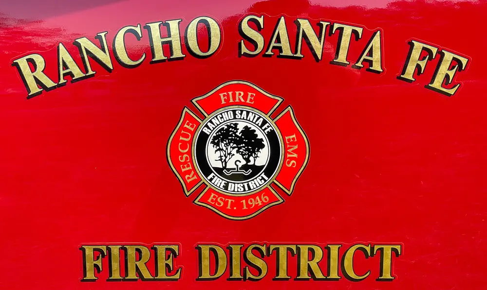 Exterior view of small fire truck showing cab, body compartments, and wheel/tire area.