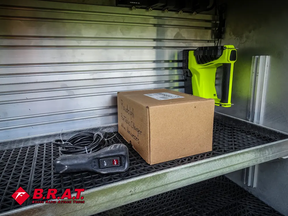 Exterior view of small fire truck showing cab, body compartments, and wheel/tire area.