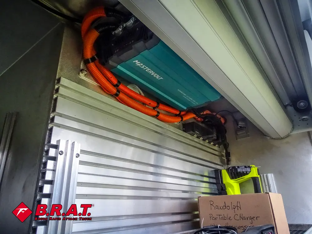 Exterior view of small fire truck showing cab, body compartments, and wheel/tire area.